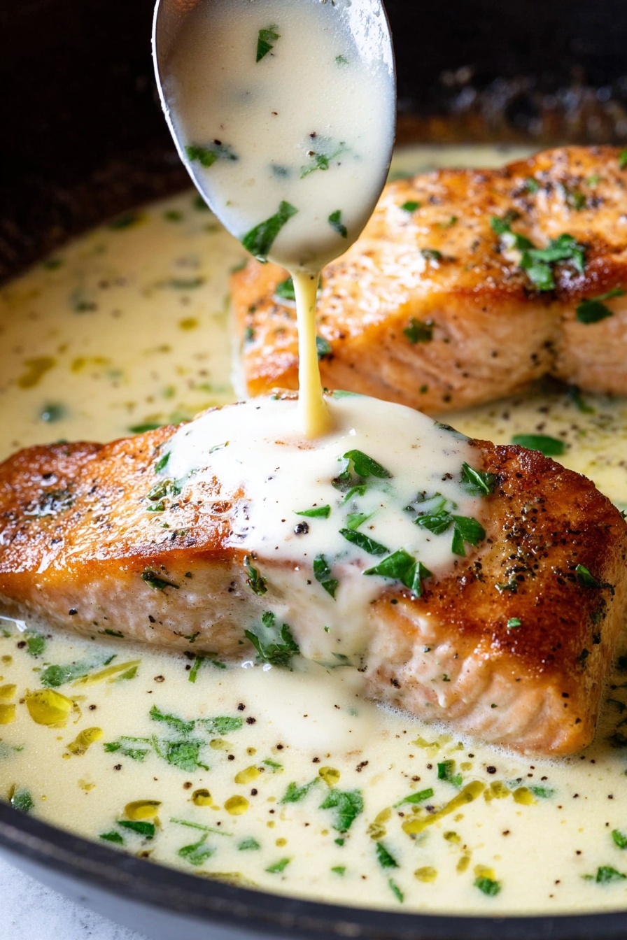 Garlic Butter Salmon - A close-up view of two cooked salmon fillets with a crispy golden-brown surface, lying flat in a white creamy sauce inside a pan. The sauce is being poured over the fillet from a spoon above, showing a smooth, thick texture with green herbs scattered throughout. Small chopped green parsley leaves and black pepper bits are sprinkled over the salmon and the sauce, adding color contrast. The background shows the dark edge of the pan, and the base beneath the pan is a white marbled texture. Photo taken with an iphone --ar 2:3 --v 7