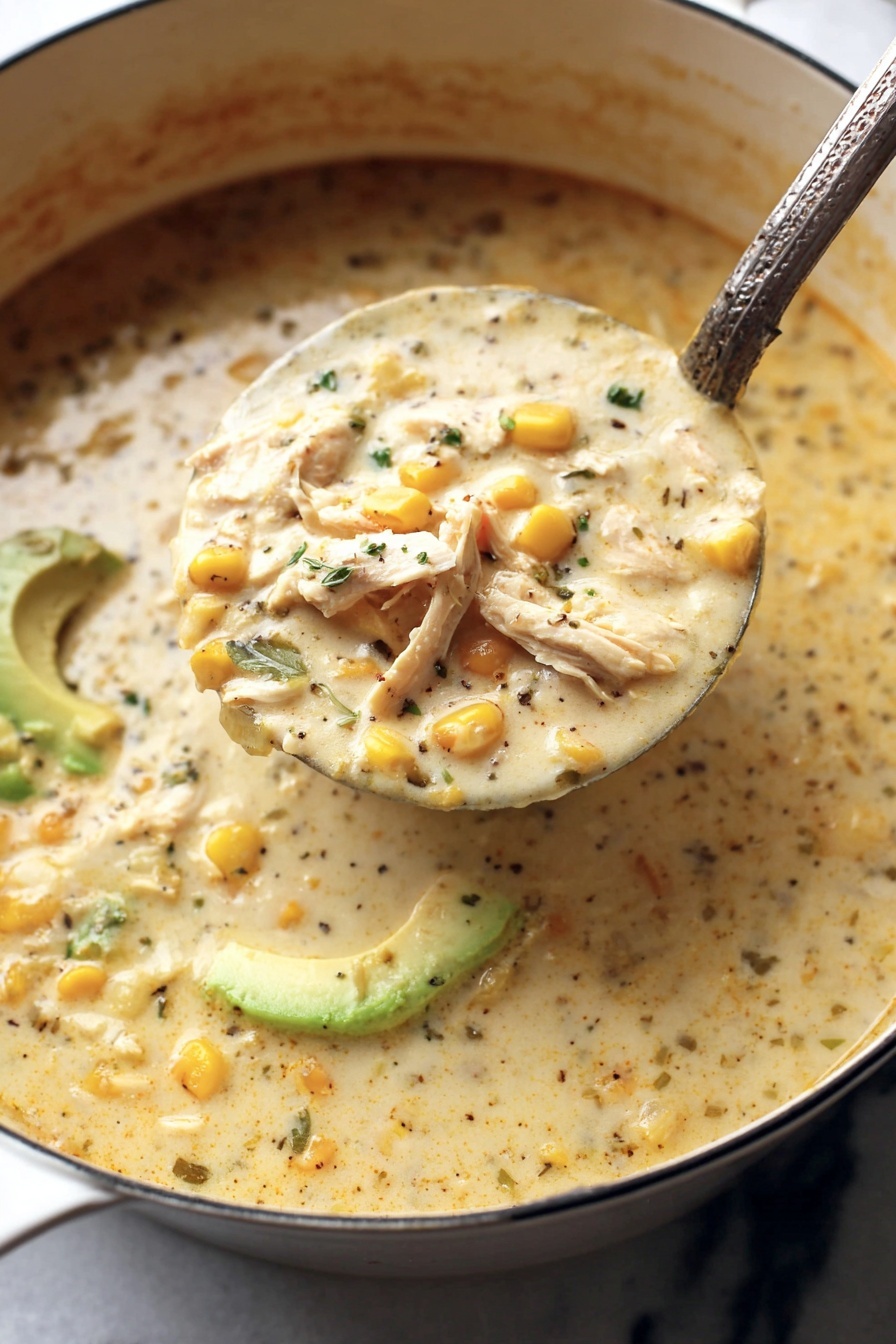white chicken chili - A large ladle filled with thick creamy soup is being lifted from a white pot, showing three main layers: light creamy broth with specks of black pepper and chopped herbs, soft yellow corn kernels scattered throughout, and shredded white meat pieces visible near the surface. In the background, sliced green avocado adds a fresh color contrast. The soup’s texture looks rich and smooth with some visible small chunks. The pot sits on a white marbled surface. Photo taken with an iphone --ar 2:3 --v 7