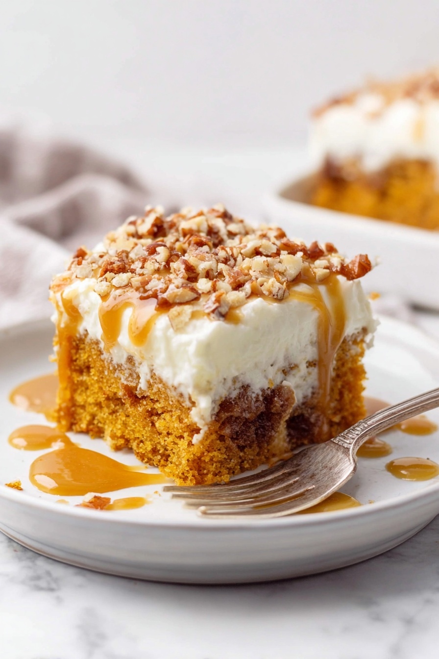 A square piece of orange-brown cake sits on a white plate with a gold fork to the left. The cake has two main layers: a moist, crumbly orange-brown base and a thick, creamy white frosting on top. The frosting is sprinkled with small pieces of brown pecans, with some pecans scattered around the plate. Golden caramel sauce is drizzled over the frosting and plate, pooling in areas around the cake. The background is a white marbled surface with a white baking dish holding more cake blurred in the back, along with decorative pumpkins and scattered pecans. Photo taken with an iphone --ar 2:3 --v 7