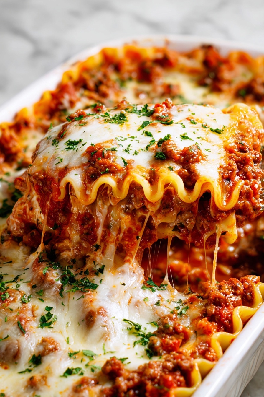 The image shows a close-up of a white baking dish filled with several rolled pasta pieces covered in thick red tomato sauce mixed with bits of cooked meat. Each roll is topped with a melted layer of white cheese that looks soft and slightly browned. Fresh green chopped herbs are sprinkled evenly over the cheese, adding color contrast. The sauce is rich and chunky, with visible tomato pieces and bits of meat that make the dish look hearty. The rolled pasta edges are visible under the sauce and cheese layers, adding texture. A golden spoon is lifting one piece from the dish, showing the layers inside with saucy pasta, meat, and cheese. The dish is set on a white marbled surface. photo taken with an iphone --ar 2:3 --v 7