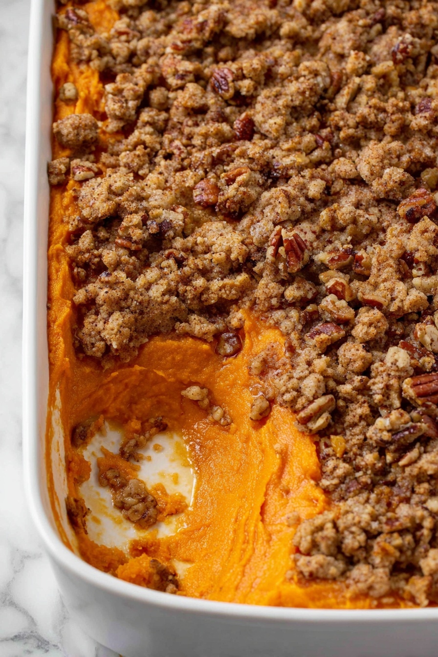 The image shows a white rectangular dish filled with a two-layer sweet potato casserole. The bottom layer is smooth, bright orange mashed sweet potatoes with a soft texture, visible where a portion has been scooped out from the corner. The top layer is a crumbly, uneven streusel topping mixed with pecan pieces, with rough, chunky textures and a golden-brown color. The contrast between the smooth sweet potato layer and the crunchy nut topping is clear. The dish is on a white marbled surface. Photo taken with an iphone --ar 2:3 --v 7