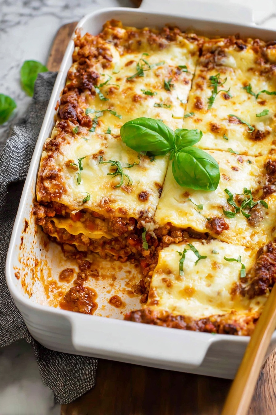 A white rectangular baking dish filled with lasagna showing multiple layers: a golden brown melted cheese layer on top with some green herb garnish, beneath it layers of light pasta sheets, a rich red tomato meat sauce mixed with ground meat, and a creamy cheese mix. A spatula lifts one slice, stretching melted cheese strings down to the rest of the dish. The dish is placed on a wooden surface next to fresh basil leaves, with a white marbled background behind. photo taken with an iphone --ar 2:3 --v 7