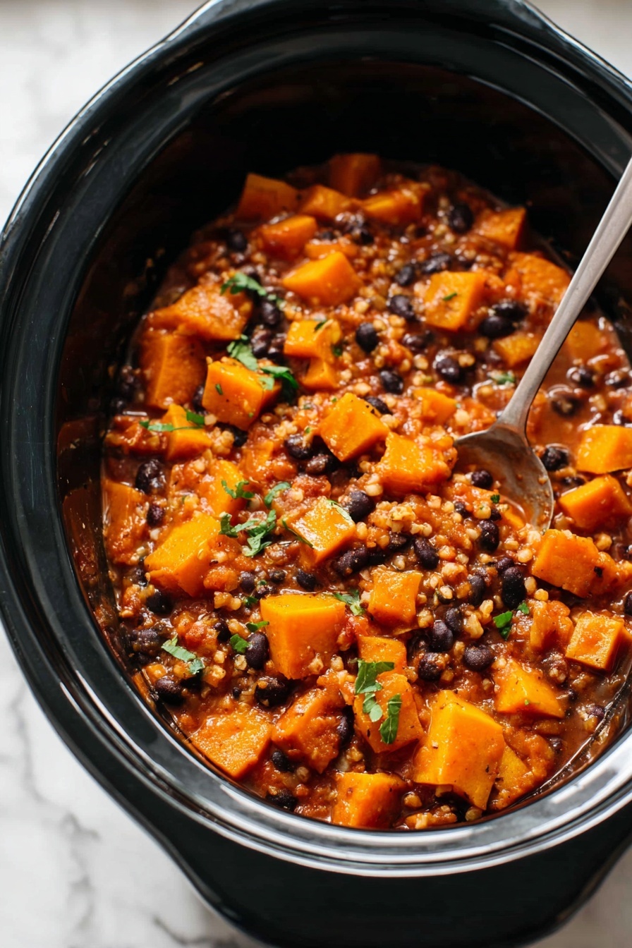 The image shows a black slow cooker filled with a chunky stew. The stew has bright orange pieces of cooked squash layered with small black beans and grains that look like barley, all mixed in a thick, reddish-brown sauce. Some green herbs are sprinkled on top for color. A metal spoon is partially submerged on the right side inside the slow cooker. The slow cooker is sitting on a surface with a white marbled texture. photo taken with an iphone --ar 2:3 --v 7