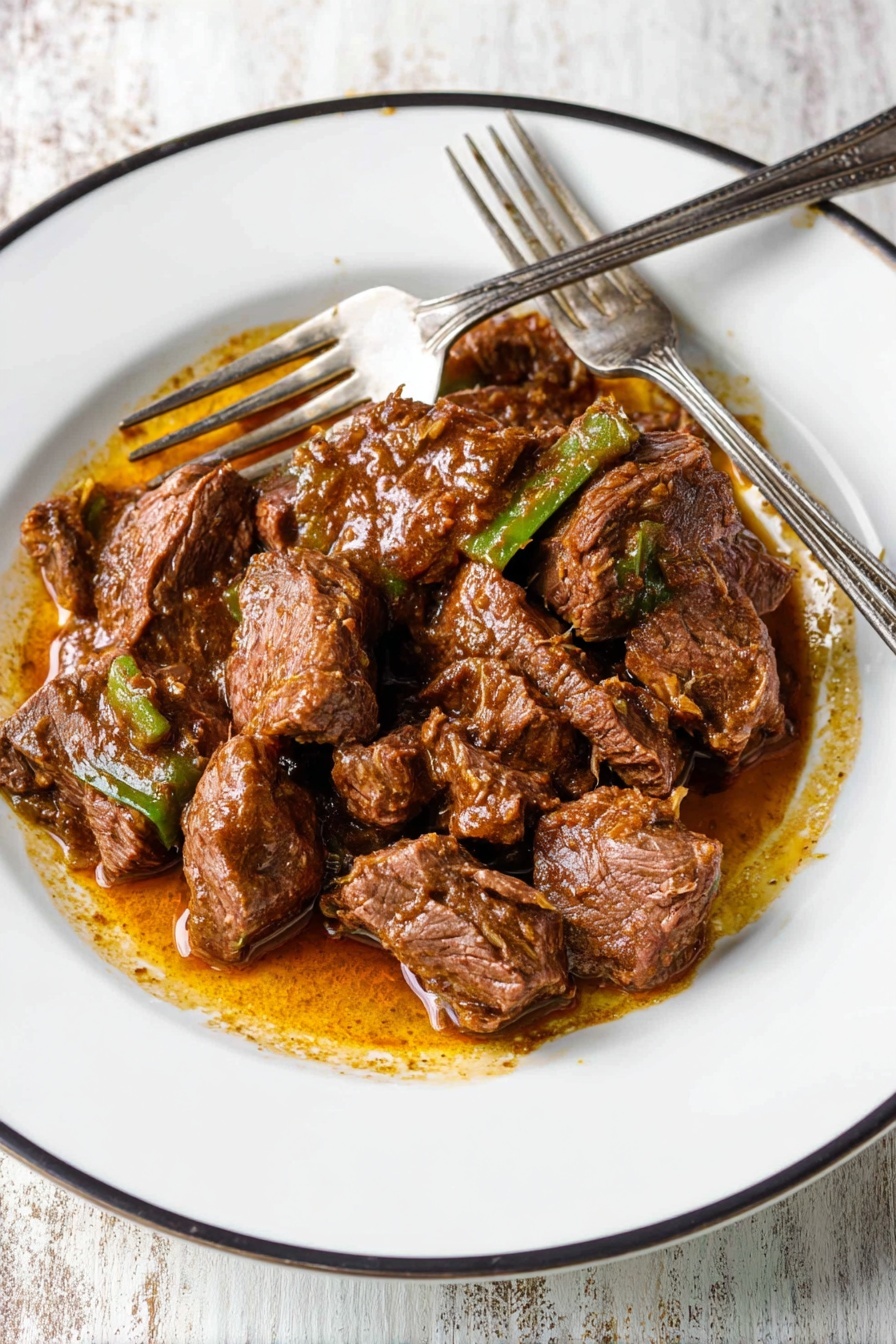 The image shows a white plate with a thin black rim filled with cooked beef chunks in a rich brown sauce with small pieces of green vegetables mixed in. The beef is cut into medium-sized pieces, some showing texture and fibers, and is coated in a slightly oily sauce that pools on the plate. Two silver forks rest on the left side of the plate, with the tines pointing into the beef. The plate is set on a white marbled textured surface. photo taken with an iphone --ar 2:3 --v 7