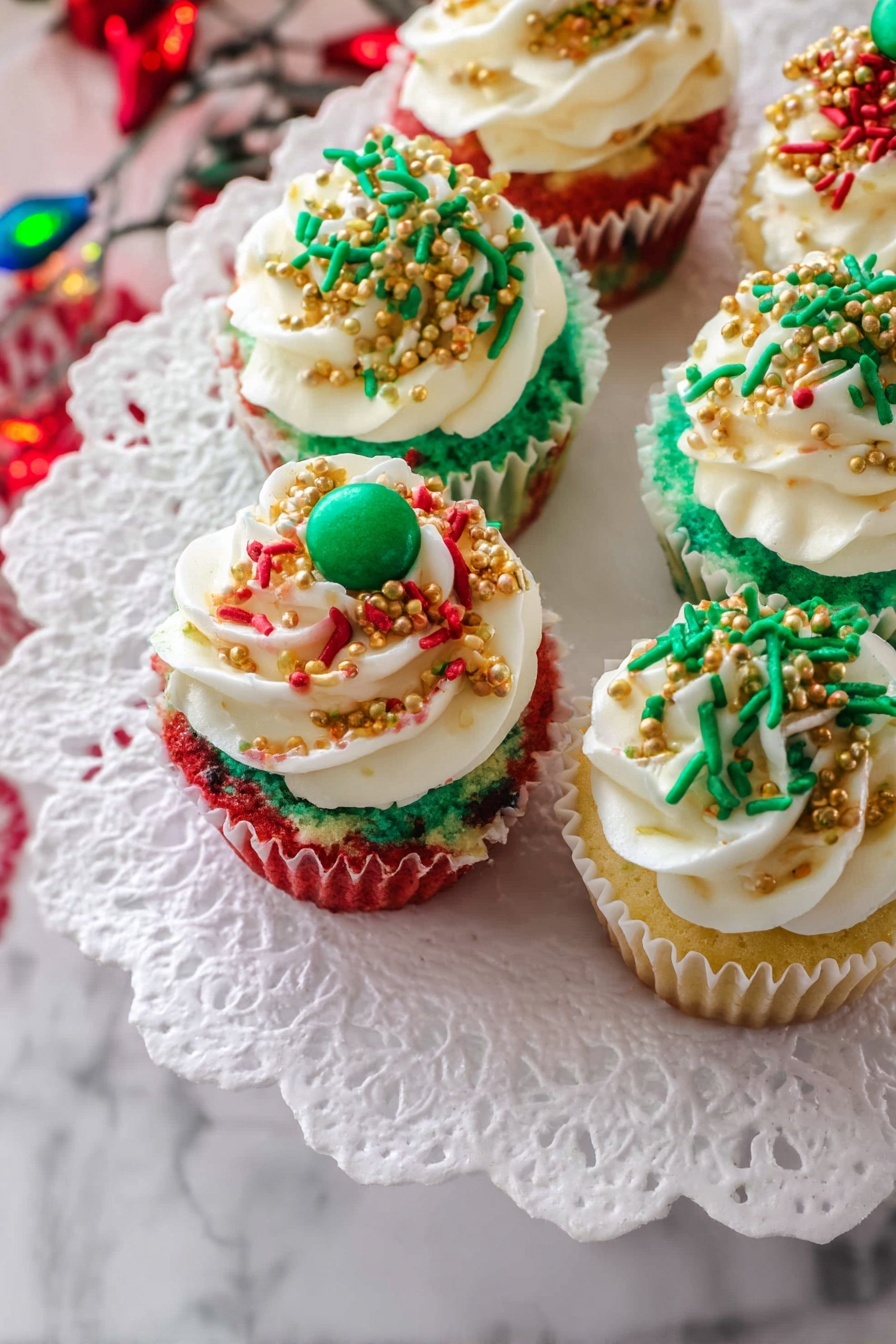 The image shows several small cupcakes arranged on a white plate with a white lace paper doily underneath. Each cupcake has three visible layers of cake in red, white, and green colors from bottom to top, creating a festive look. On top, there is a thick layer of white frosting swirled smoothly with some texture. The frosting is decorated with colorful sprinkles in red, green, and gold, along with small gold bead-like toppings. Some cupcakes have a small green round candy on top, centered in the frosting. The background features a white marbled surface with some blurred colorful holiday lights in the corner, adding a festive atmosphere. photo taken with an iphone --ar 2:3 --v 7