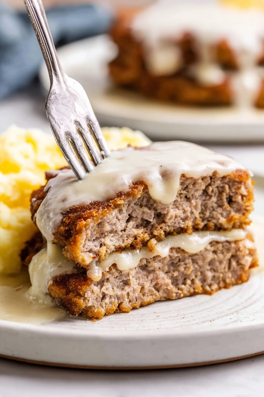 The image shows a close-up of a thick, creamy white sauce in a pan. The sauce has a smooth texture with small specks of black pepper spread throughout, giving it a slightly speckled look. A silver spoon is lifting some of the sauce, showing its thick but flowing consistency. The pan is on a stove, and the background has a white marbled texture. photo taken with an iphone --ar 2:3 --v 7