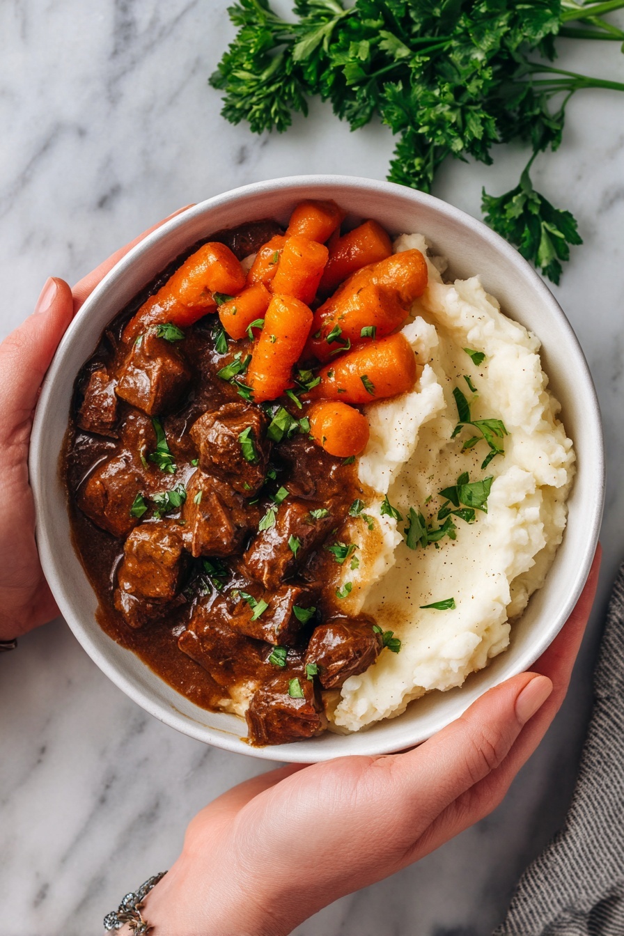 A shiny silver frying pan with a few small pieces of seared meat scattered inside, each piece showing a mix of pink and browned colors from cooking. The meat pieces are uneven in shape, with browned edges and some light sear marks on top. The pan sits on a white marbled surface, and faint steam rises from the meat, giving a fresh cooked feeling. A worn, slightly tarnished handle with a gold