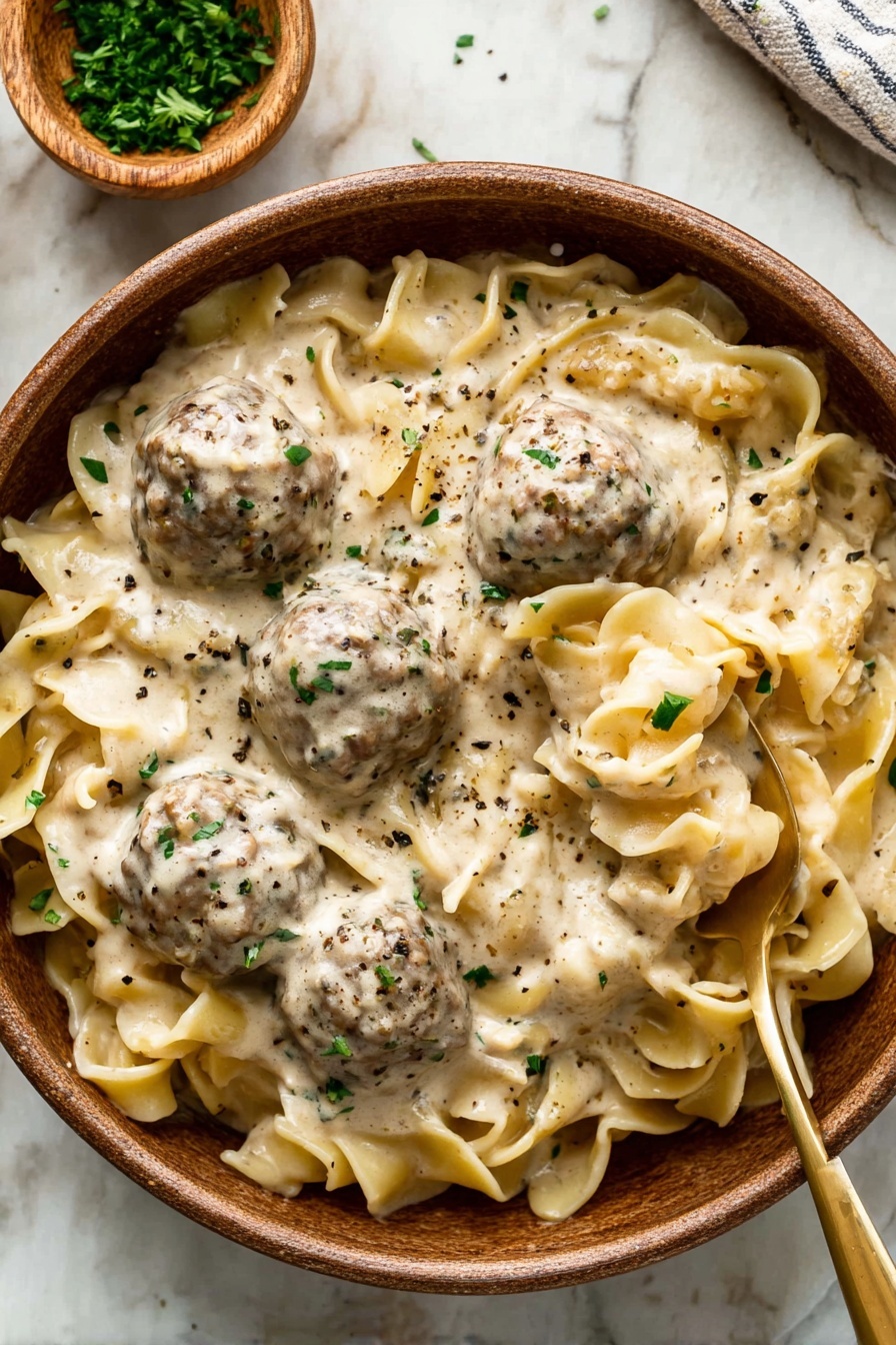 A clear glass bowl sits on a white marbled surface, filled with a mixture of raw ground meat with visible small pieces of herbs and onions mixed in, giving it a textured look of red with specks of green and white. A metal scoop holds a rounded ball of the same meat mixture above the bowl, showing the coarse and moist texture clearly. A woman's hand grips the handle of the scoop, positioned at the bottom left corner of the image. Photo taken with an iphone --ar 2:3 --v 7