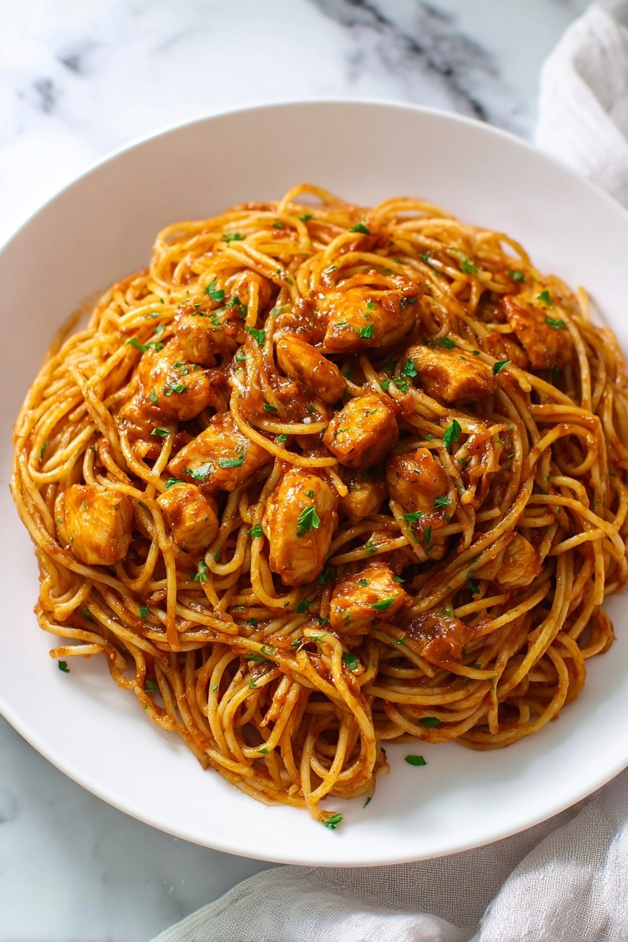 The image shows two parts: on the left, a white round plate holds many pieces of cooked chicken, light golden brown in color with a slightly crispy texture, scattered closely together covering the plate; on the right, a silver frying pan with some residue of cooking holds sautéed onions that are light brown and soft, mixed with minced garlic, dried green herbs, and black pepper, all gathered in the center of the pan, giving a sense of seasoning and preparation. The scene is set on a white marbled surface. photo taken with an iphone --ar 2:3 --v 7