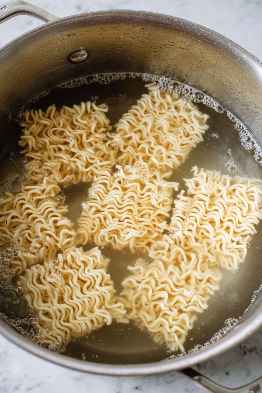 The image shows a close-up of spicy noodles lifted by wooden chopsticks from a white speckled bowl. The noodles are thick and curly, coated with a red spicy sauce. Around the noodles in the bowl are thin round slices of radish with pink edges and green herb leaves, as well as small white onion pieces. There are also some dark-colored meat pieces visible among the noodles. On the side of the bowl, a soft-boiled egg is halved, showing a bright yellow yolk. The background has a white marbled texture. photo taken with an iphone --ar 2:3 --v 7